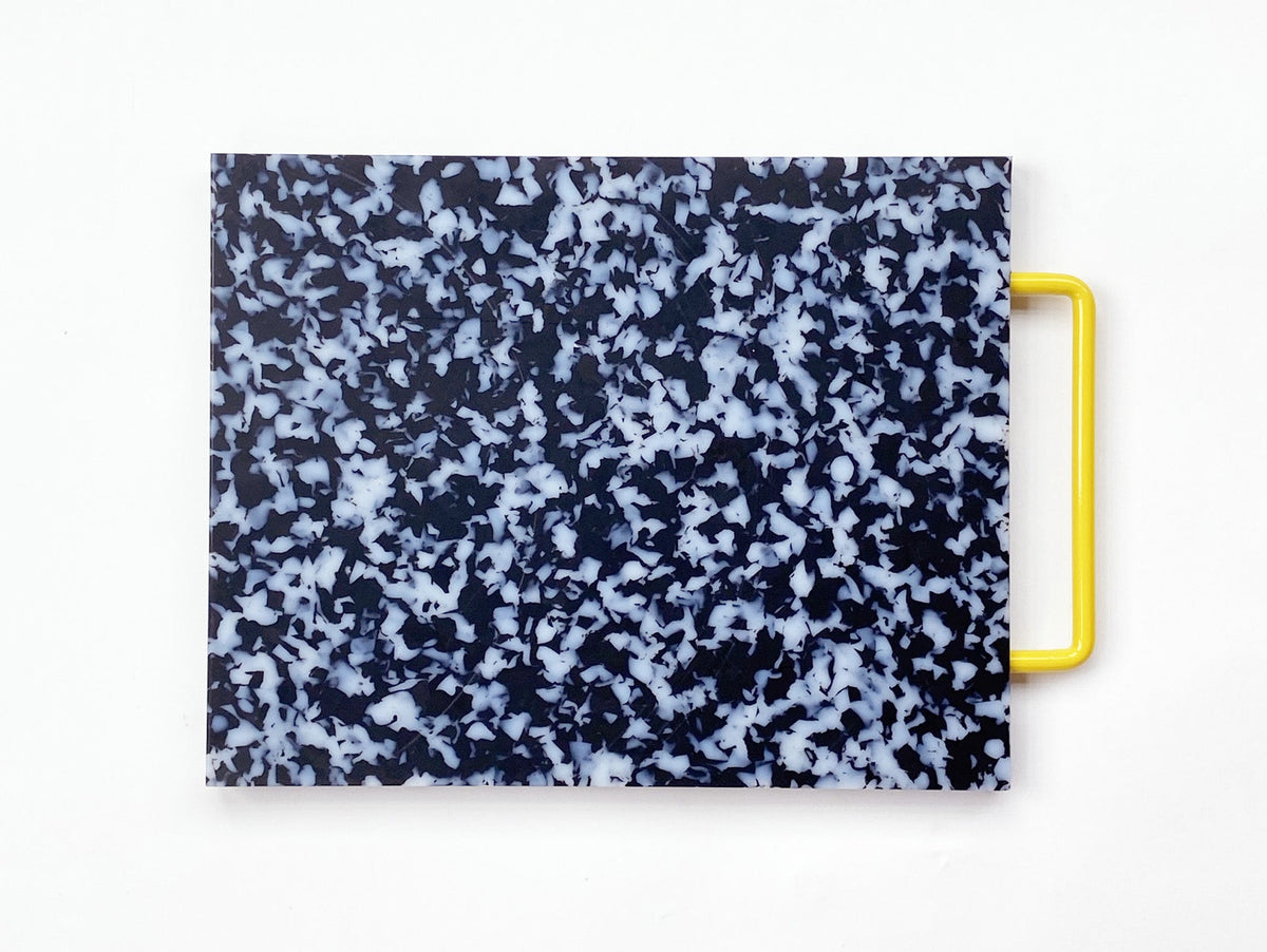 black and white cutting board with a yellow handle on a white background